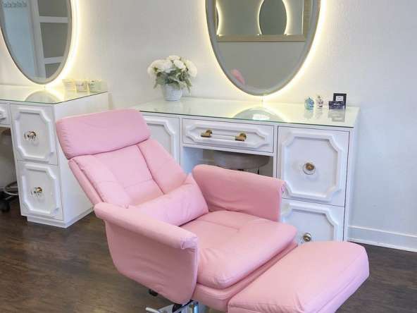 Comfortable pink styling chair in a modern salon setting with mirrors and floral decor.