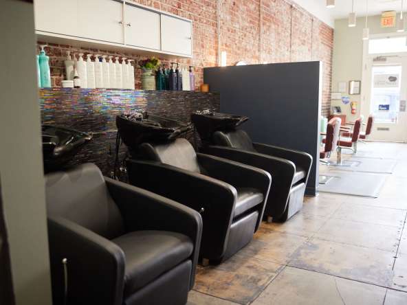 Professional hair washing station with black chairs and salon supplies in a modern salon setting.