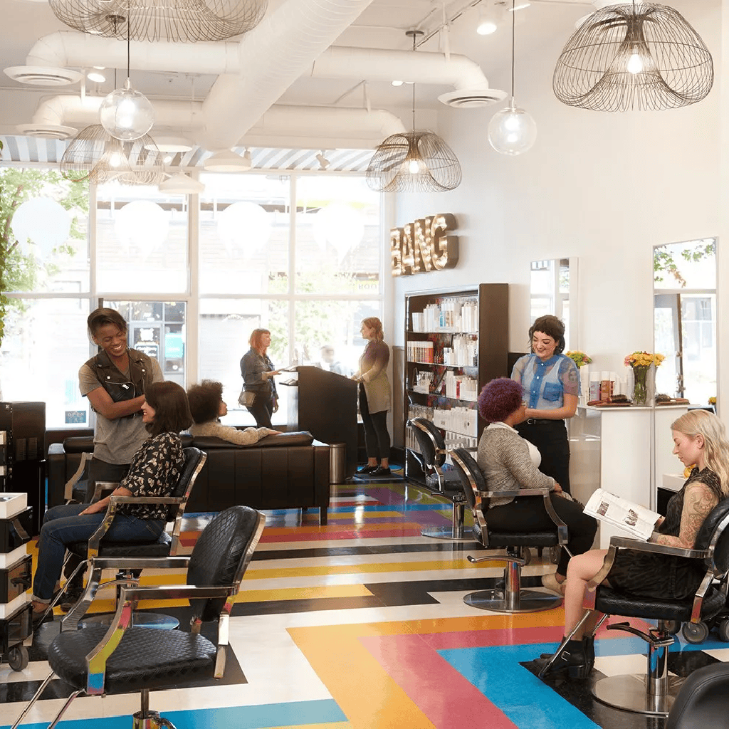 Bright, welcoming salon with diverse clients, stylish decor, and friendly staff in a vibrant, colorful setting.