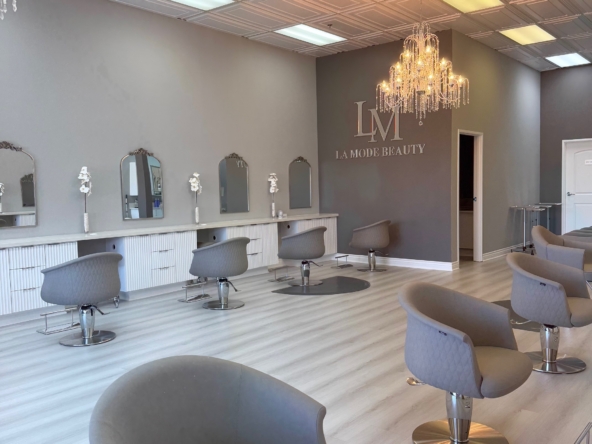 Stylish salon with comfortable chairs, mirrors, and chandelier for beauty services.