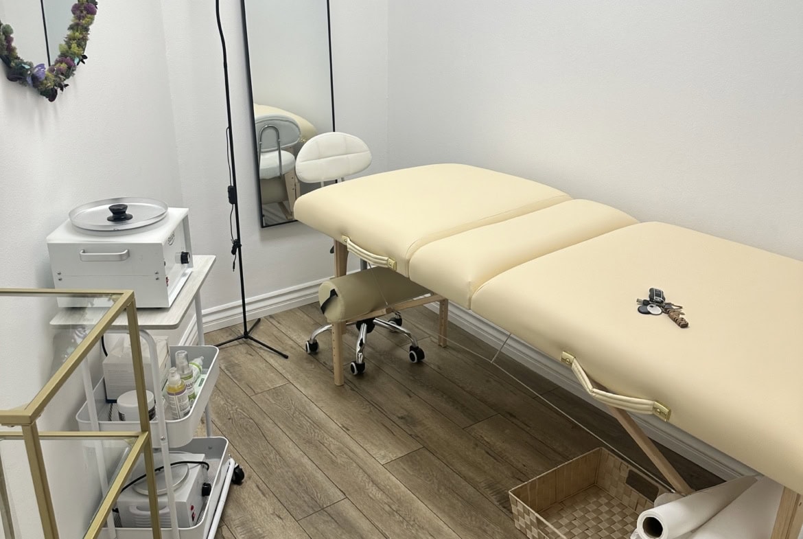 Clean, stylish massage therapy room with treatment bed, mirror, and therapeutic supplies.