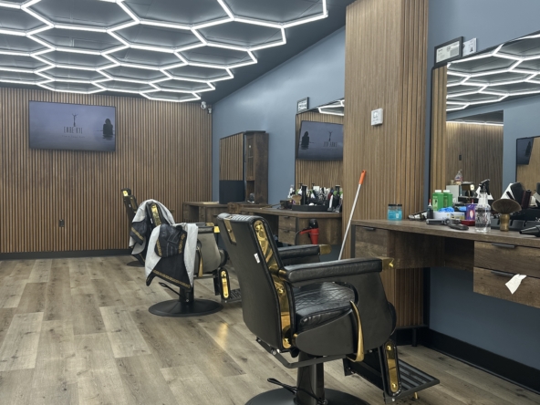 Stylish salon interior featuring black leather chairs, wooden accents, and innovative hexagon LED ceiling design for a luxurious beauty experience.
