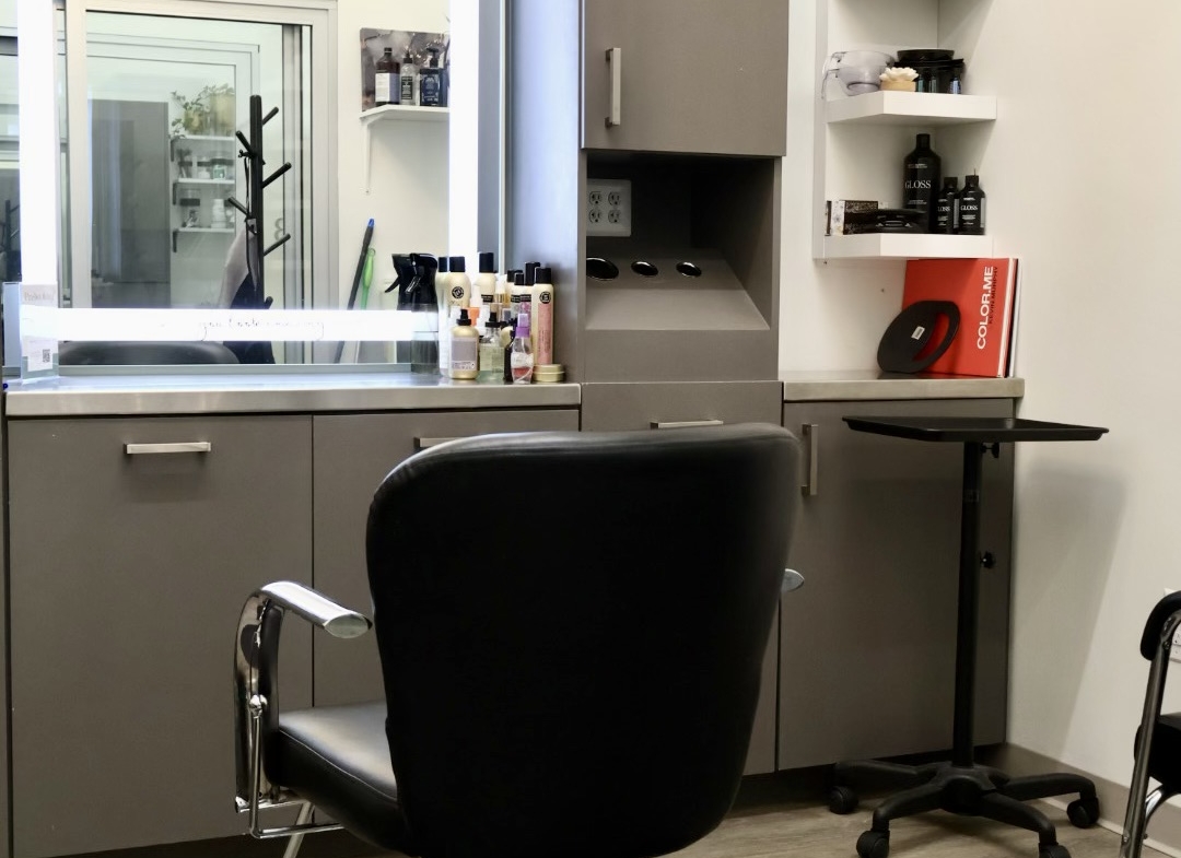 A professional salon workspace featuring a styling chair, mirror, and hair care essentials.