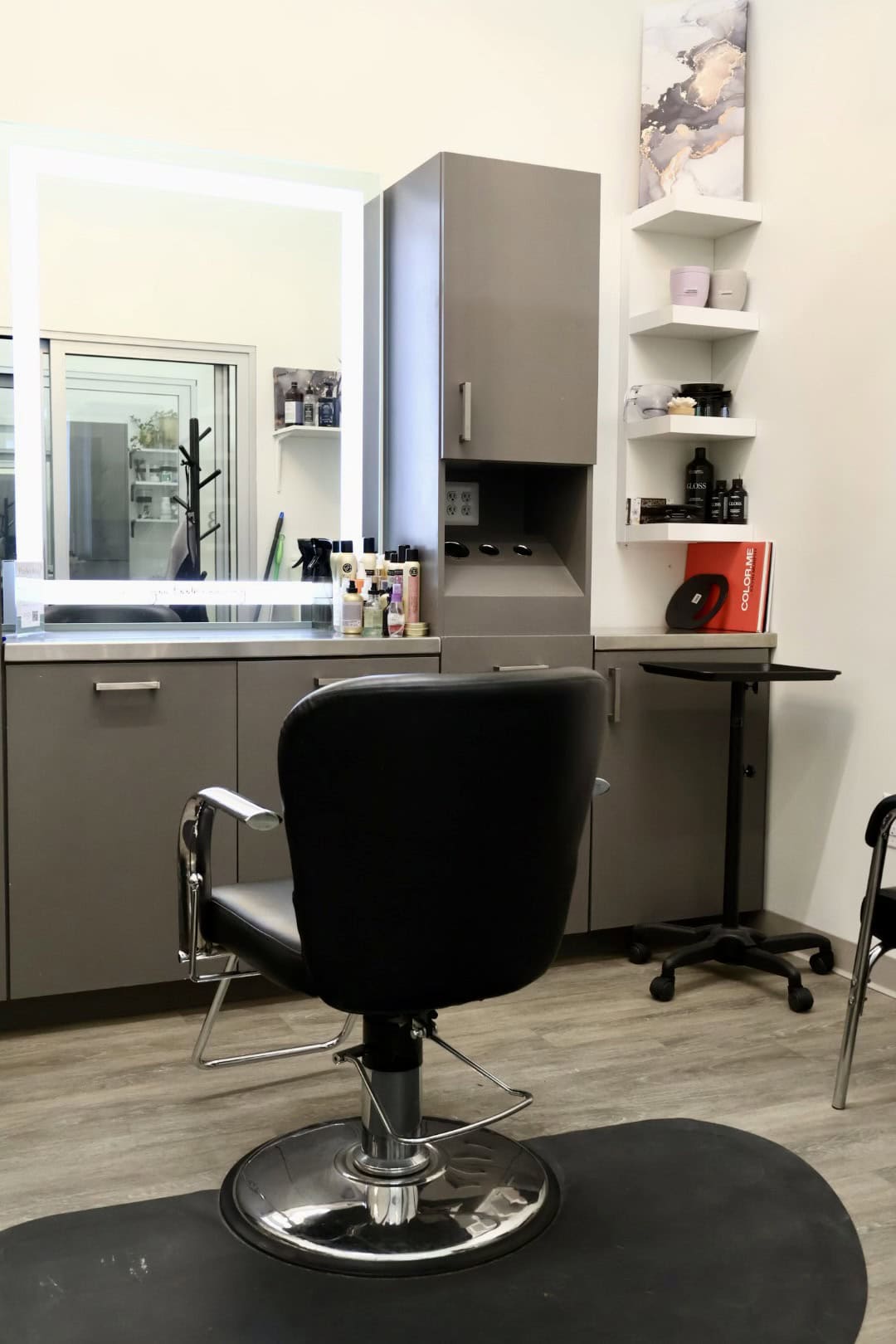 A professional salon workspace featuring a styling chair, mirror, and hair care essentials.