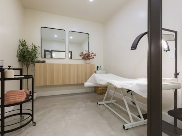 A clean, modern salon rental space with treatment table, mirrors, and stylish decor for beauty professionals.