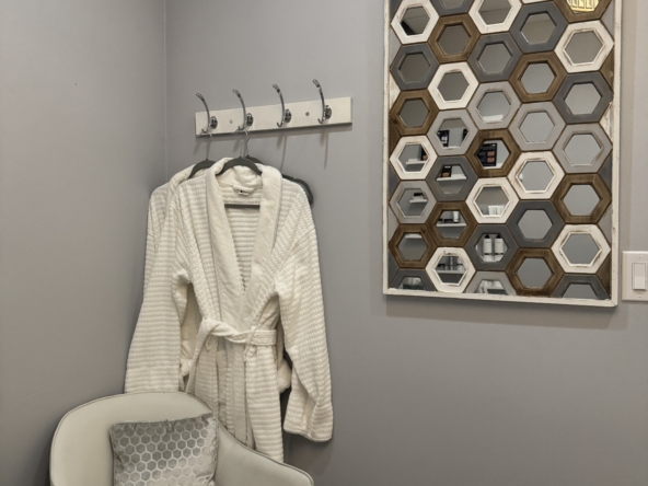 Elegant salon waiting room with robe, mirror, and cozy chair for clients.