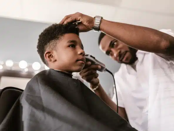 Professional barber cutting young boy's hair at salon.