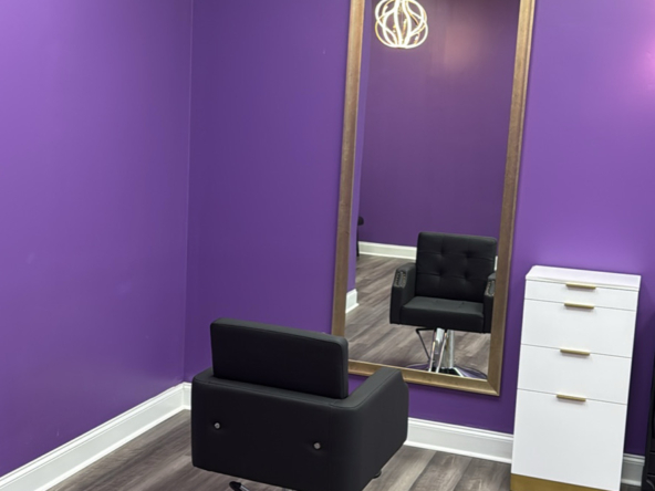 Stylish salon chair and full-length mirror in vibrant purple-walled beauty space.