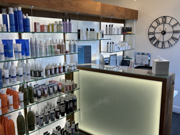 Bright salon interior with product displays, sleek reception desk, and contemporary lighting.