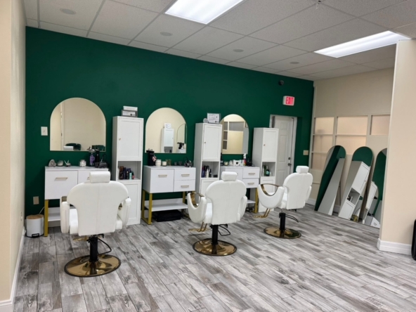 1. Modern salon station with white chairs and green accent wall for hair styling.