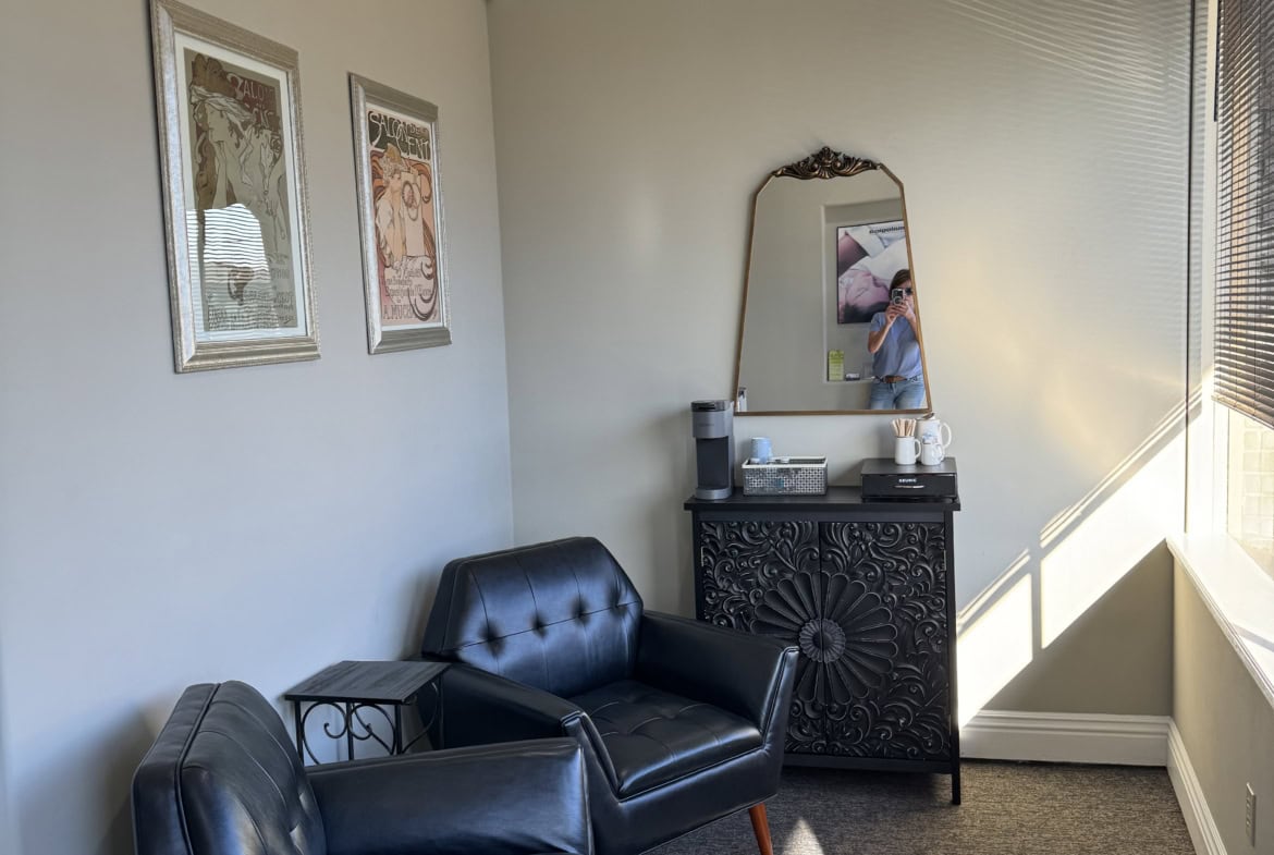 Cozy salon waiting area with leather chairs and decorative wall art for clients.