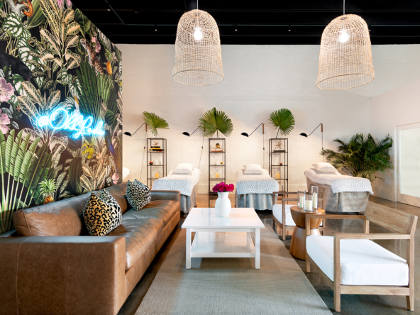 Bright salon lounge with tropical decor, massage beds, and vibrant greenery, ideal for salon rentals.