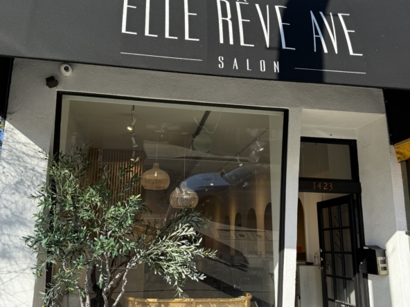 Chic salon storefront with modern black awning and stylish interior visible through large window.