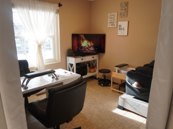 Cozy salon break room with TV, comfortable chairs, natural light, and motivational decor.