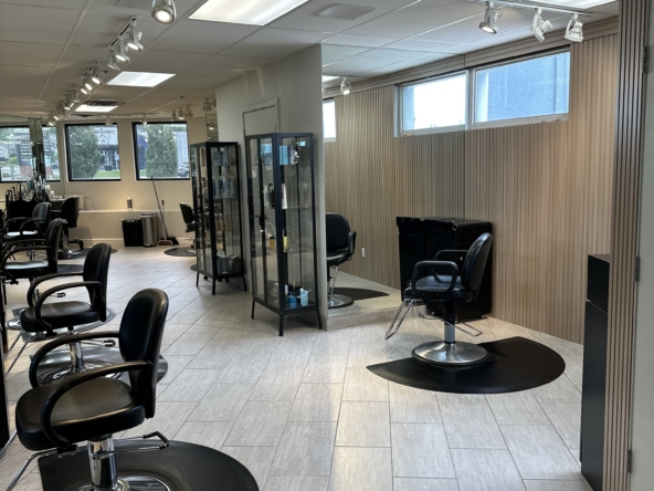 Stylish salon space with modern styling chairs and glass display cabinets for hair products.