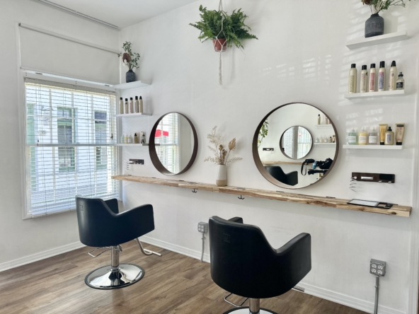 Bright salon station with modern decor, mirrors, and hair products for rent at Salon Renter.
