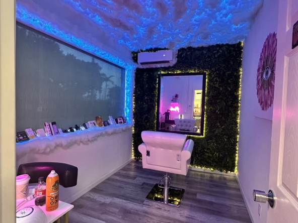 Stylish salon interior featuring cloud ceiling with blue LED lights, plush chair, and decorative wall for a relaxing beauty environment.