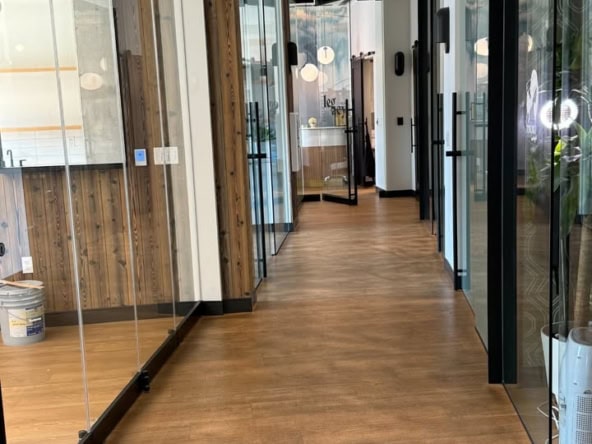 Modern salon hallway with glass doors and wood accents, ideal for salon rental spaces.