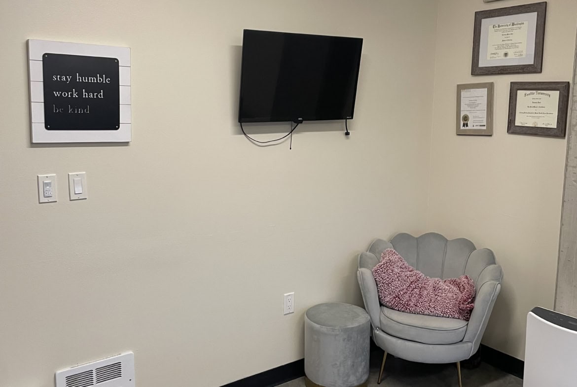Cozy salon renter consultation space with wall-mounted TV, framed certificates, and comfortable seat.
