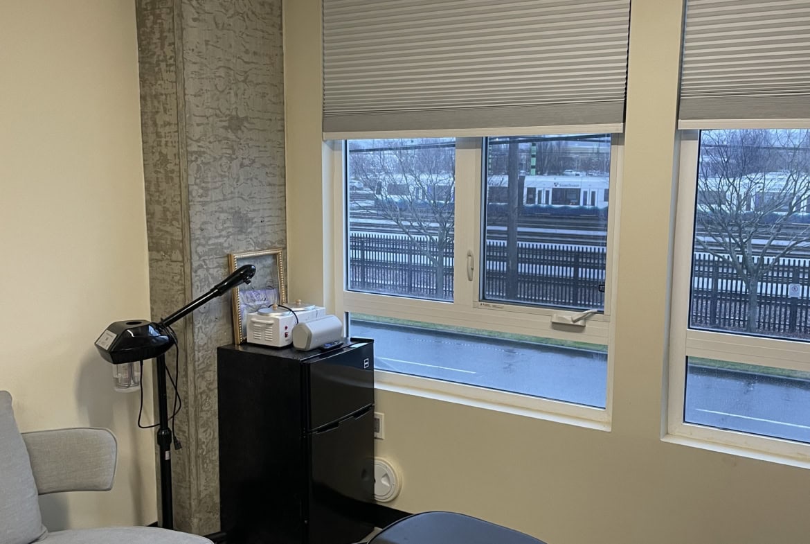 Beauty treatment room with large windows, comfortable chair, and professional equipment.