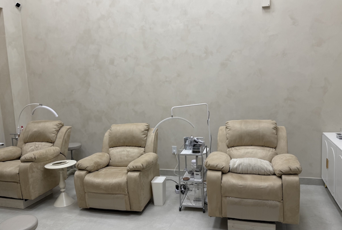 Comfortable beige salon lounge chairs with armrests and footrests for client relaxation.