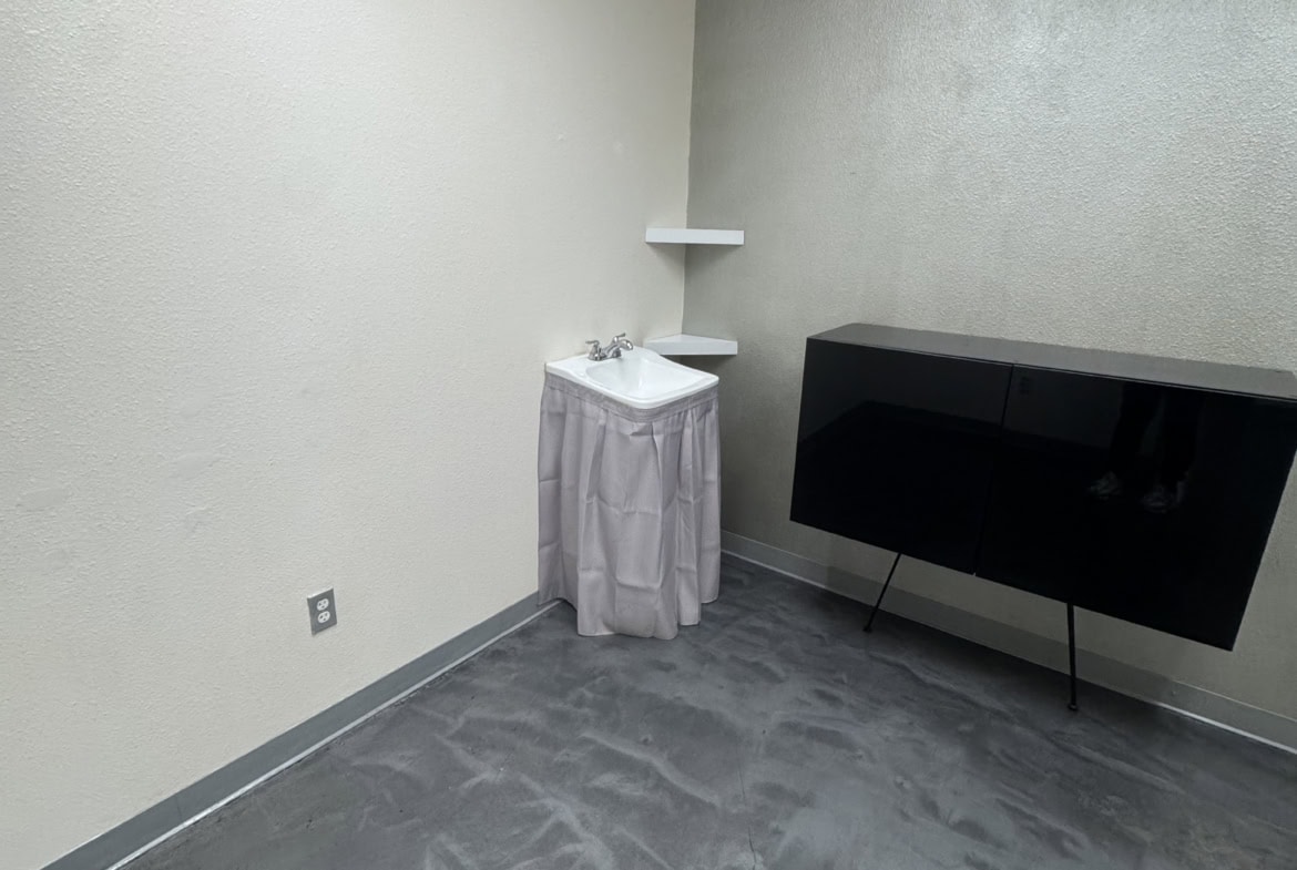 Empty salon room with sink and modern black cabinet for hair styling.