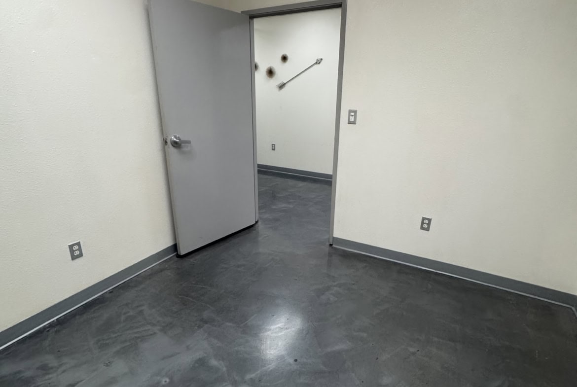 Empty salon room with gray flooring and white walls, ready for styling stations.