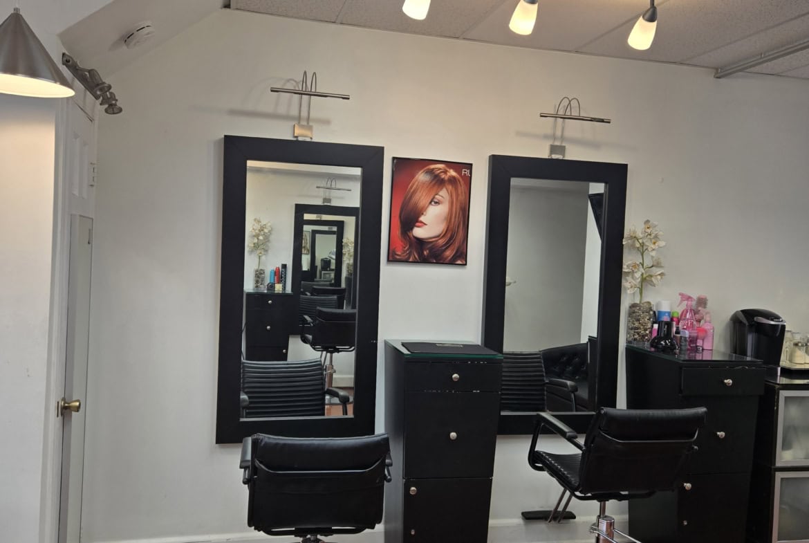 Modern salon styling stations with mirrors and chairs for haircuts and styling.