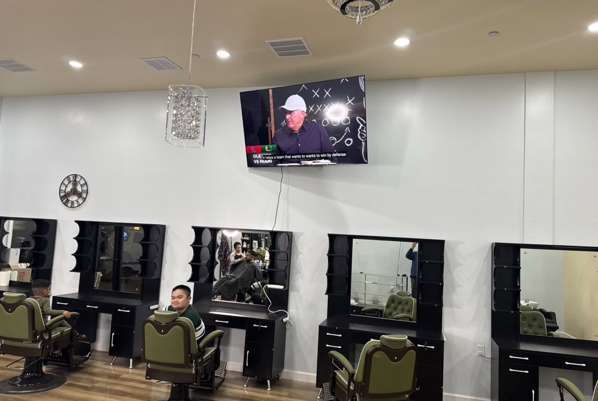 Modern hair salon station with styling chairs, mirrors, and a TV for customer entertainment.