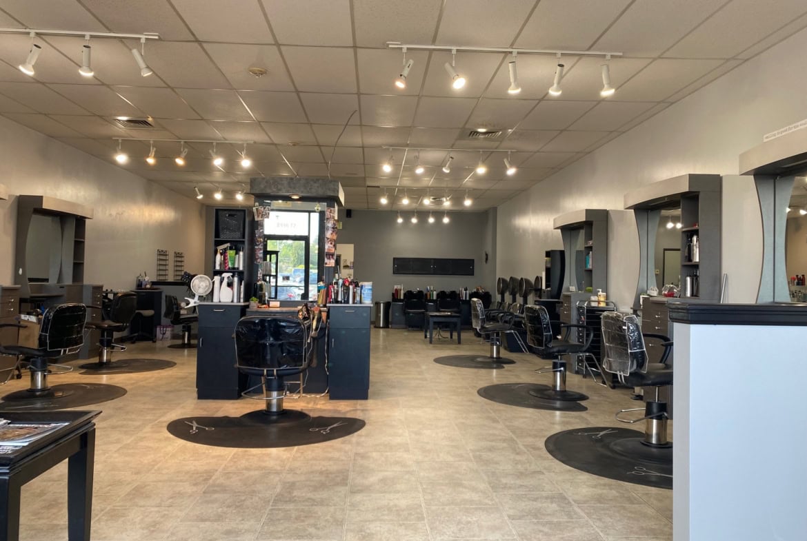 Modern hair salon interior with styling stations, chairs, and mirrors for haircuts and styling.