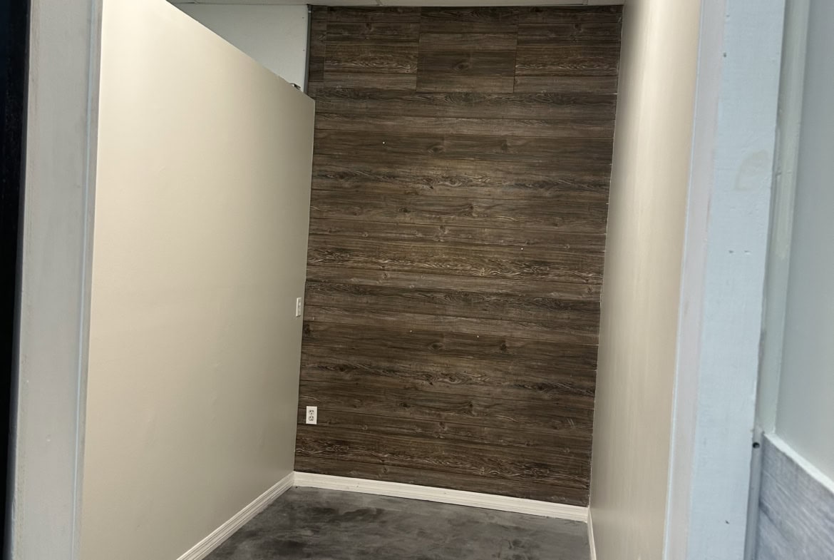 Small salon room with neutral-colored walls and a wood accent wall, ideal for styling or consultatio.