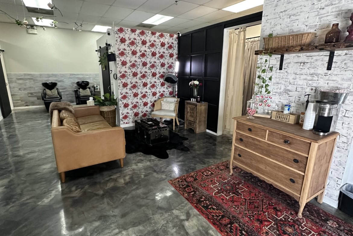 Salon Renter interior with cozy seating, decorative wallpaper, and professional styling area.