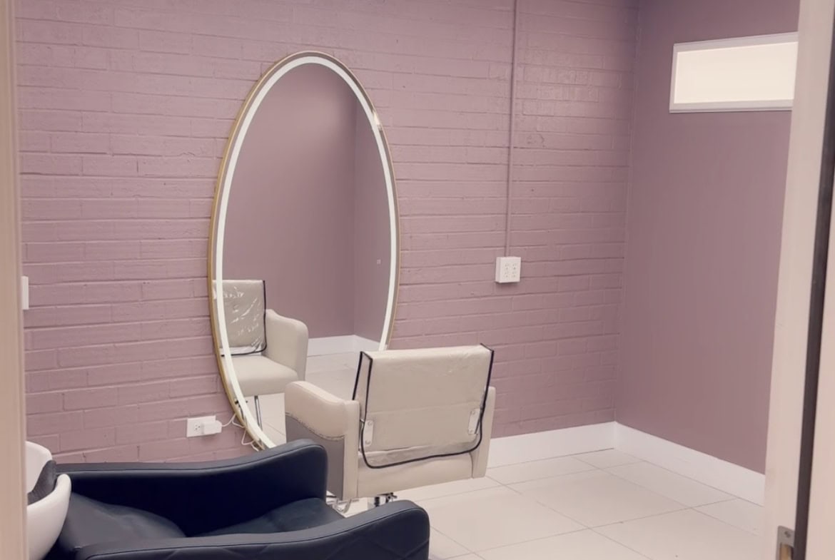 Stylish salon space featuring a comfortable styling chair and large oval mirror for hair and beauty.