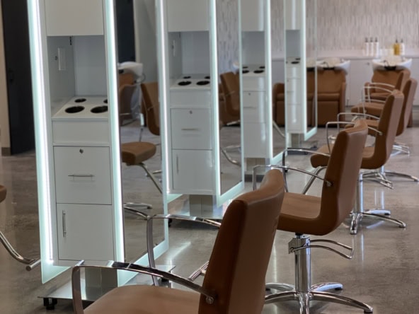 Stylish salon stations with mirrors and comfortable chairs for professional haircuts and styling.