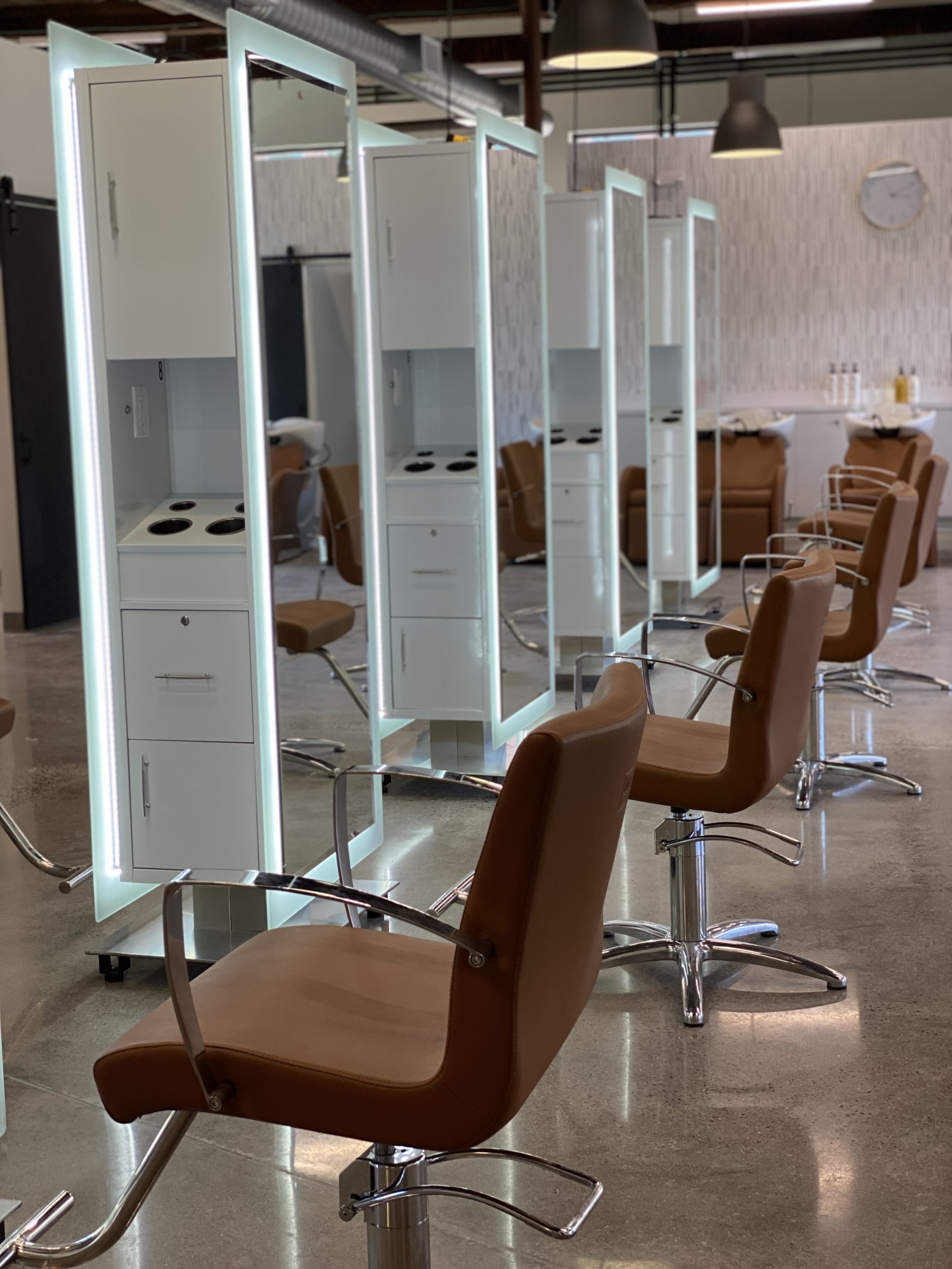Stylish salon stations with mirrors and comfortable chairs for professional haircuts and styling.