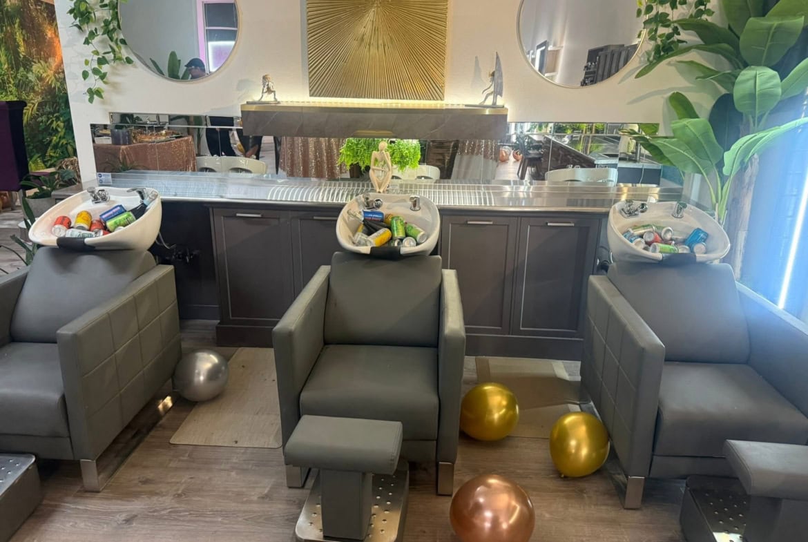 Modern salon lounge with comfortable chairs, decorative gold and bronze spheres, and stylish mirrors.