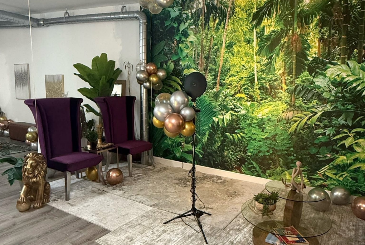 Vibrant salon space featuring a jungle-themed wall mural, stylish chairs, and festive balloon decora.