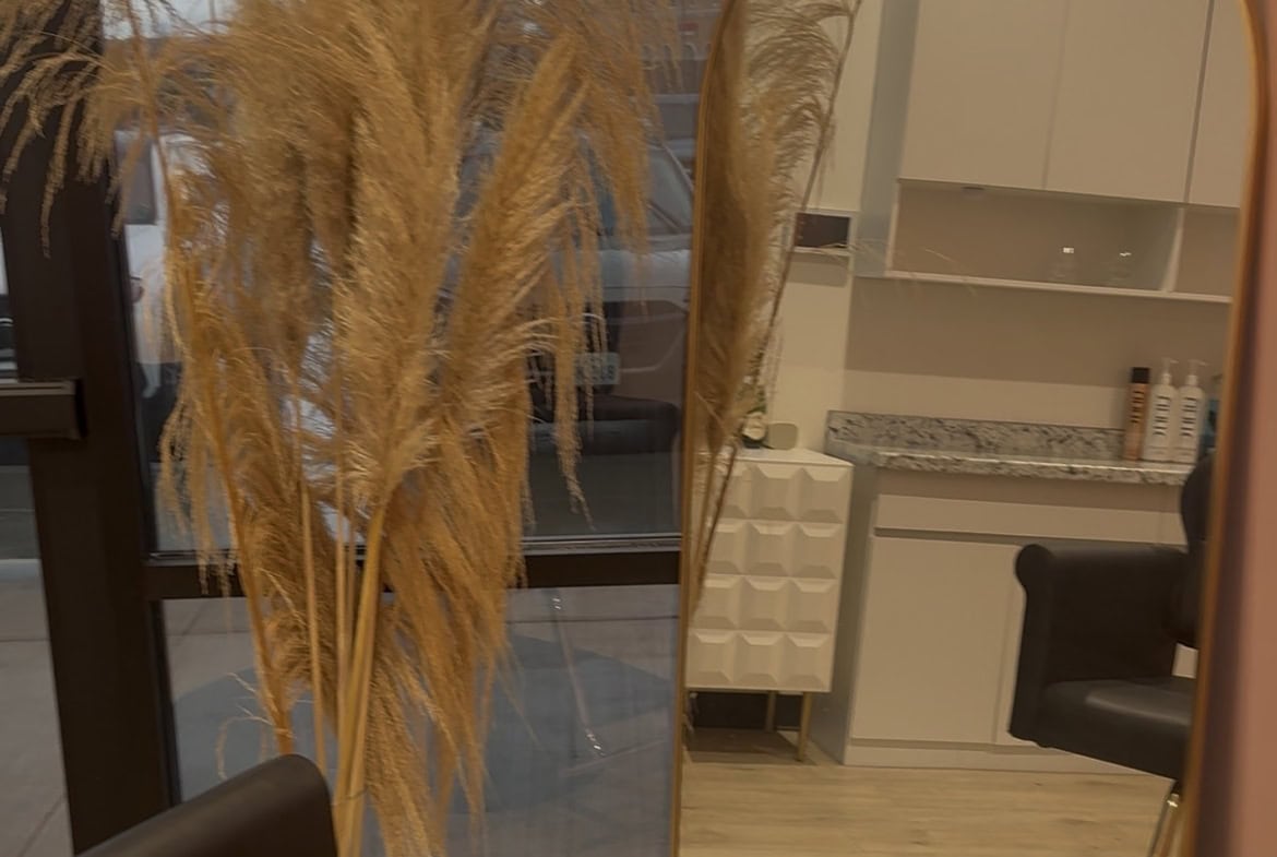 Modern salon interior with pampas grass decor and large mirror for hair styling.