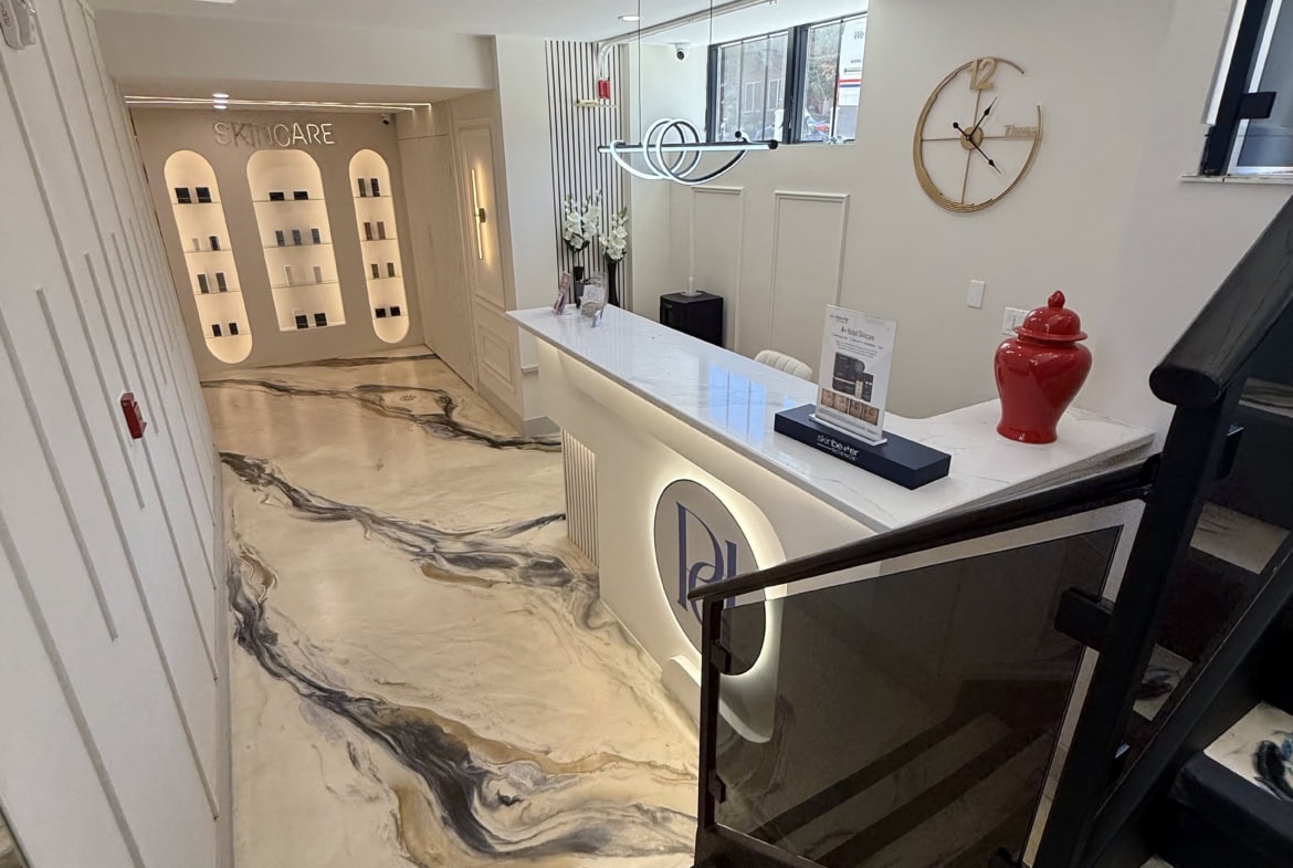 Modern salon reception with marble floors and stylish decor, featuring a front desk, wall clock, and.