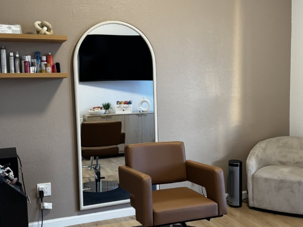 Salon Renter styling station with mirror and comfortable chair for haircuts and styling services.
