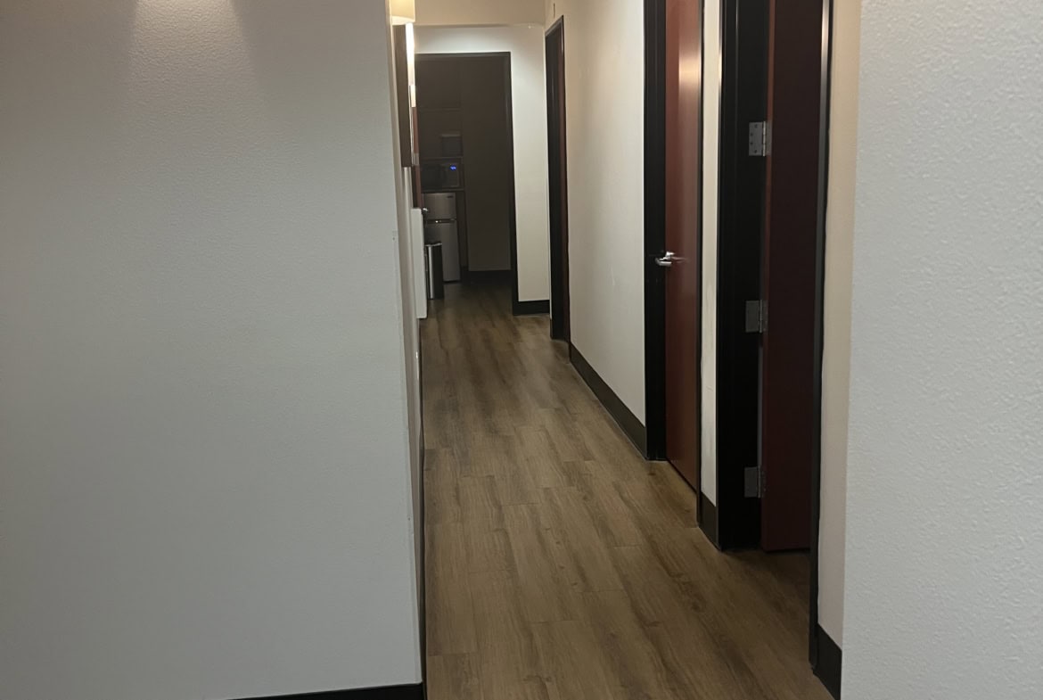 Hallway with doors in a salon rental space, featuring contemporary lighting and wood flooring.
