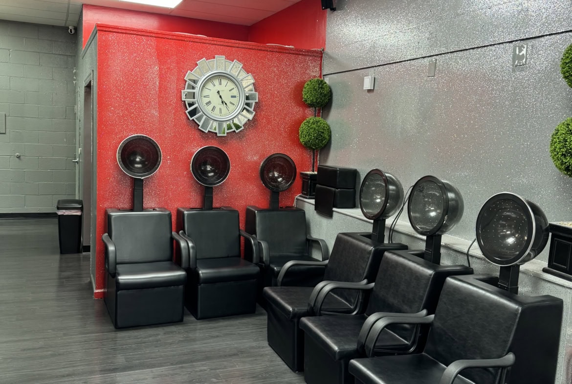 Modern salon waiting area with black chairs, wall clock, and stylish decor.