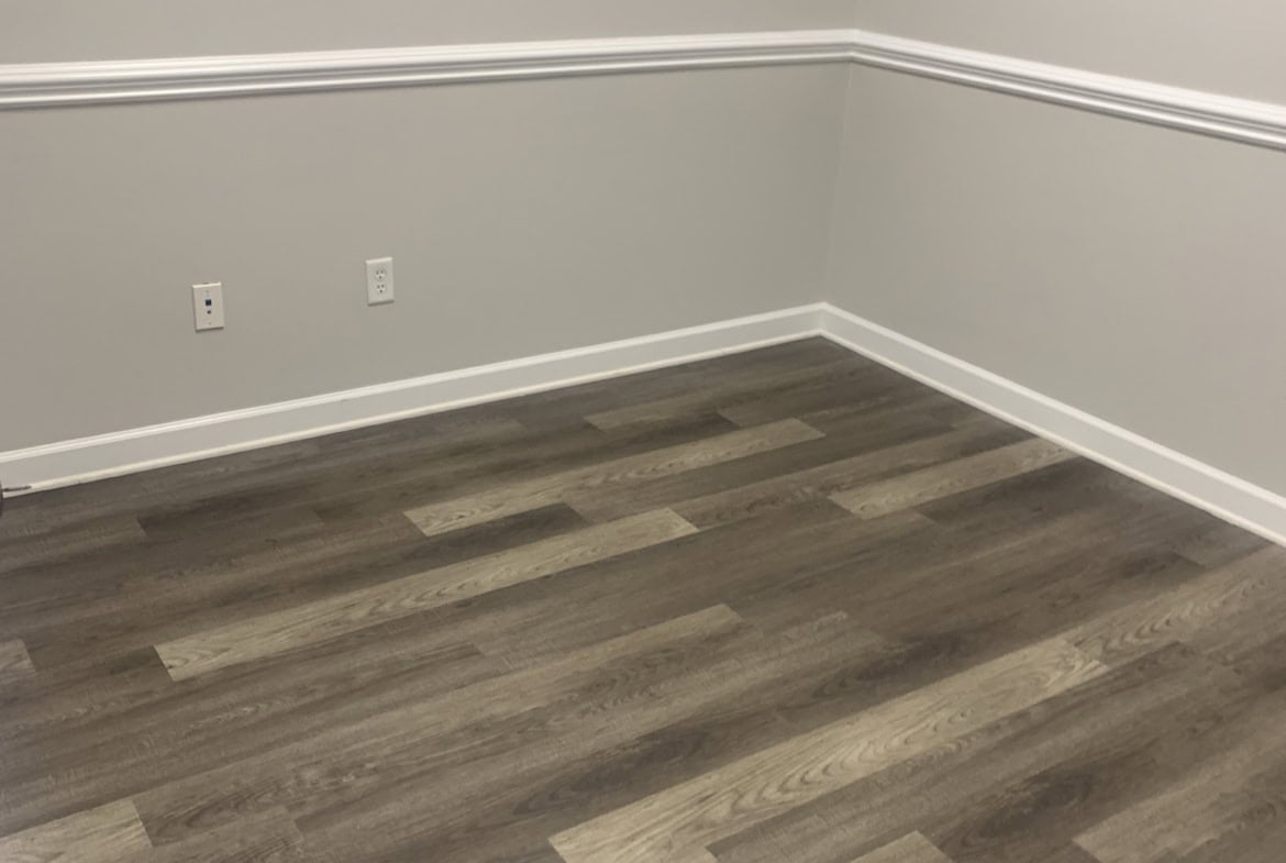 Empty salon room with gray walls and wood flooring. Perfect space for a beauty or hair salon setup.