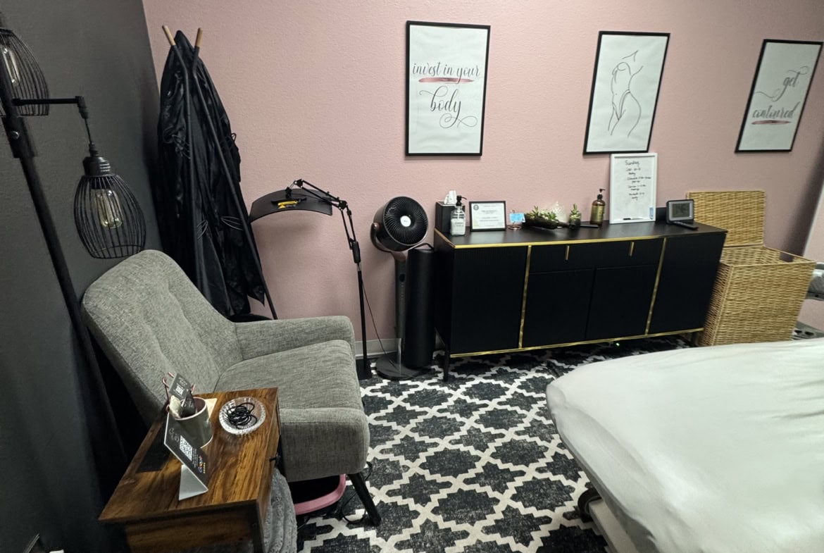 Cozy salon treatment room with massage bed, seating, and decor.