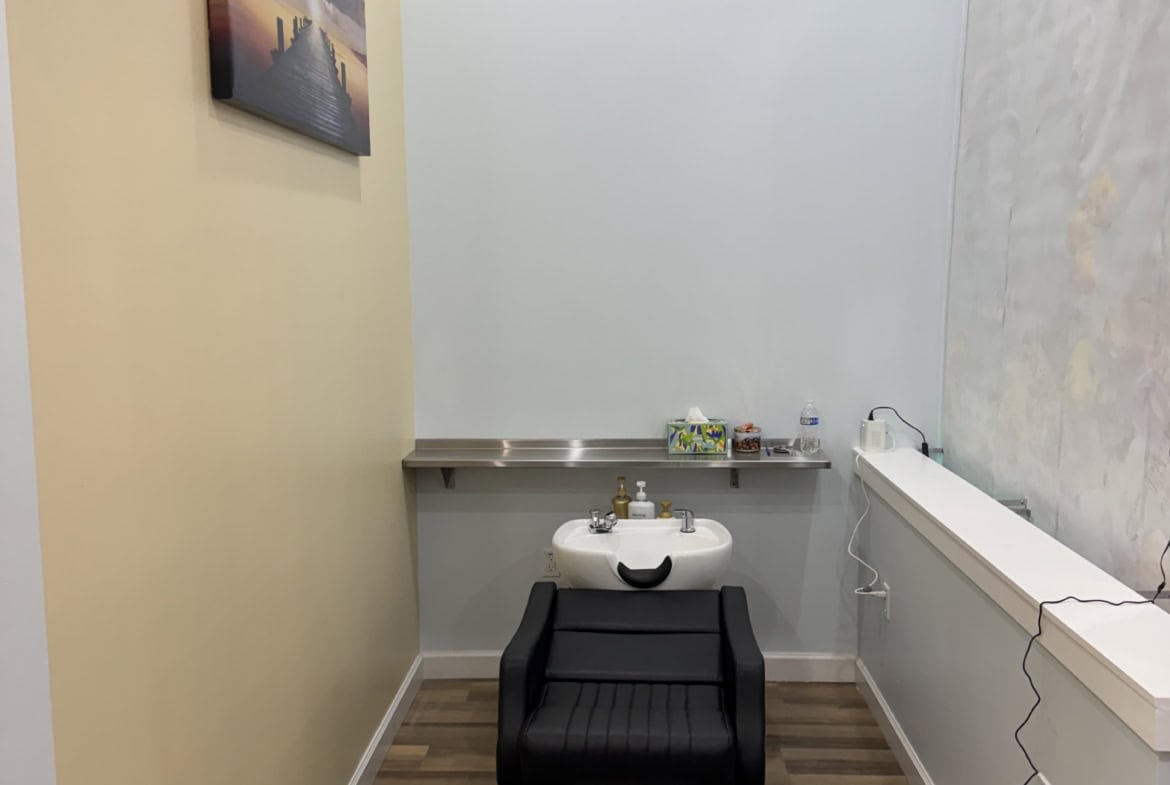 Hair washing station in a salon rental space with a sink and comfortable chair.