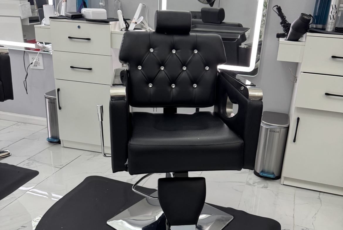 Barber chair in a salon with white cabinets and styling tools.