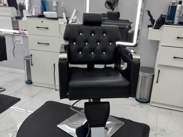 Barber chair in a salon with white cabinets and styling tools.